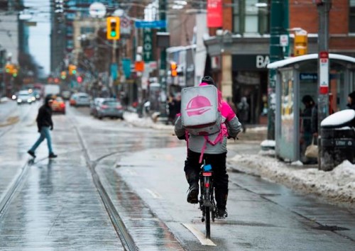 A Foodora courier is pictured as they pick up an order for delivery from a restaurant in Toronto, Feb. 27, 2020. When Phil Warner, Jordyn Samuels and Umar Asghar started hitting the road for ride-hailing and delivery apps in 2016, they quickly found their experiences negatively compared with their white and male counterparts. THE CANADIAN PRESS/Nathan Denette