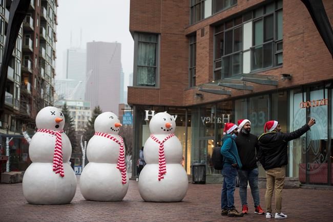 A group wearing Santa hats stops to take a selfie next to snowmen displayed at the Distillery District in Toronto on Christmas Eve, Thursday, Dec. 24, 2020. The most wonderful time in a not-so-wonderful year has arrived and Canadians from coast to coast aren't letting the pandemic put a damper on their Christmas spirit. THE CANADIAN PRESS/Tijana Martin