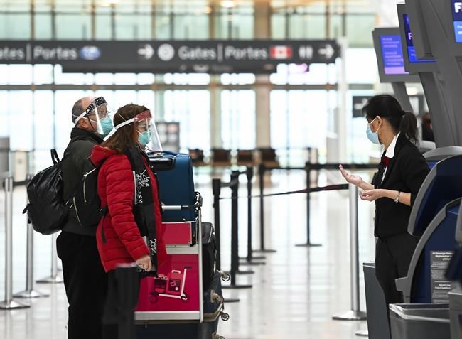 People wearing protective equipment check in at the international departures at Pearson International Airport during the COVID-19 pandemic in Toronto on Monday, December 14, 2020. THE CANADIAN PRESS/Nathan Denette