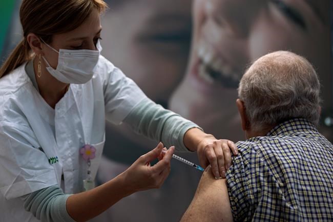 A man receives a COVID-19 vaccine from medical staff at a COVID-19 vaccination center in Tel Aviv, Israel, Wednesday Jan. 6, 2021. THE CANADIAN PRESS/AP/Oded Balilty