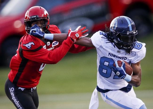 Toronto Argonauts' Derel Walker, right, holds off Calgary Stampeders' Robertson Daniel, during second half CFL football action in Calgary, Thursday, July 18, 2019. THE CANADIAN PRESS/Jeff McIntosh