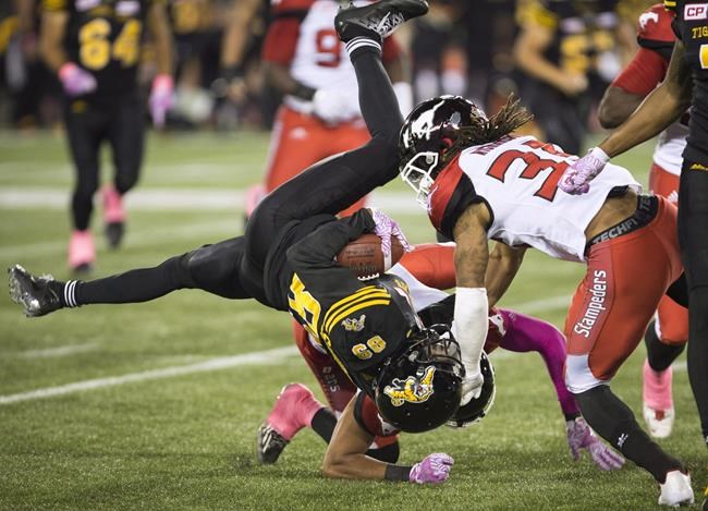 Hamilton Tiger-Cats wide receiver Jalen Saunders (89) is upended after getting hit by Calgary Stampeders defensive back Ciante Evans (0) during first half CFL football action in Hamilton, Ont., on Friday, October 13, 2017. The Ottawa Redblacks have re-signed linebacker Jerod Fernandez, Saunders and running back Timothy Flanders.THE CANADIAN PRESS/Peter Power