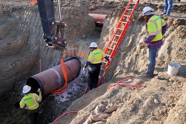In this April 13, 2020, photo provided by TC Energy, construction contractors for TC Energy are seen installing a section of the Keystone XL crude oil pipeline at the U.S.-Canada border north of Glasgow, Mont. THE CANADIAN PRESS/AP-TC Energy via AP