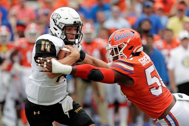 Towson quarterback Tom Flacco (14) is stopped by Florida linebacker Jonathan Greenard, right, during the first half of an NCAA college football game, Saturday, Sept. 28, 2019, in Gainesville, Fla. The Saskatchewan Roughriders have signed American quarterback Flacco.Flacco joins the Roughriders after two strong seasons at Towson Unitversity in Maryland. THE CANADIAN PRESS/AP/John Raoux