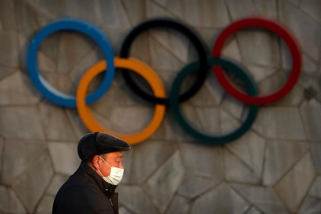 A man wearing a face mask to protect against the coronavirus walks past the Olympic rings on the exterior of the National Stadium, also known as the Bird's Nest, which will be a venue for the upcoming 2022 Winter Olympics, in Beijing on February 2, 2021. THE CANADIAN PRESS/AP, Mark Schiefelbein