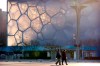 People walk past the Water Cube, which will be known as the Ice Cube when it hosts events for the 2022 Beijing Winter Olympics, in Beijing, Tuesday, Feb. 2, 2021. Canada will not boycott the 2022 Winter Games in Beijing despite calls from human rights organizations to do so. THE CANADIAN PRESS/AP/Mark Schiefelbein