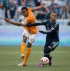 Houston Dynamo's Ricardo Clark, left, passes the ball while under pressure from Vancouver Whitecaps' Russell Teibert during the first half of an MLS soccer game in Vancouver, B.C., on Saturday March 29, 2014. THE CANADIAN PRESS/Darryl Dyck