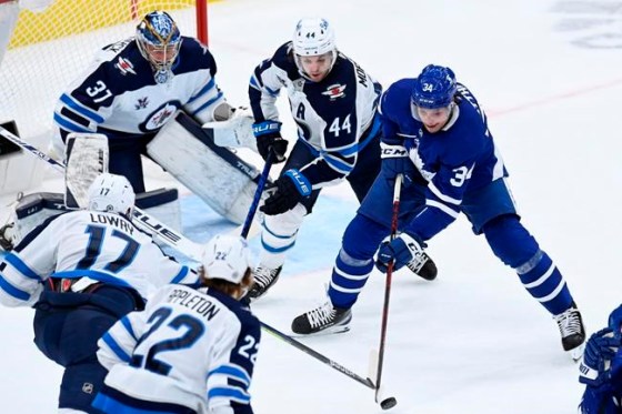 Toronto Maple Leafs centre Auston Matthews (34) battles for control of the puck against Winnipeg Jets left wing Adam Lowry (17) and Jets defenceman Josh Morrissey (44) during first-period NHL action in Toronto on Thursday, March 11, 2021. THE CANADIAN PRESS/Frank Gunn