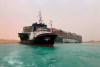 In this photo released by the Suez Canal Authority, a boat navigates in front of a cargo ship, Ever Given, Wednesday, March 24, 2021, after it become wedged across Egypt’s Suez Canal and blocked all traffic in the vital waterway. An Egyptian official warned Wednesday it could take at least two days to clear the ship. THE CANADIAN PRESS/Suez Canal Authority via AP