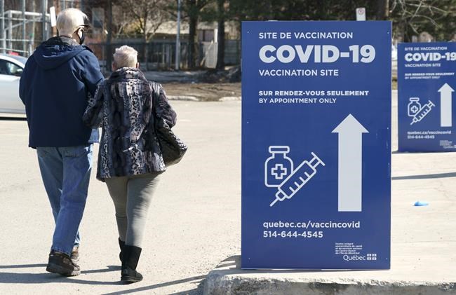 A couple walks to a COVID-19 vaccination clinic in Montreal, on Tuesday, March 23, 2021. THE CANADIAN PRESS/Paul Chiasson