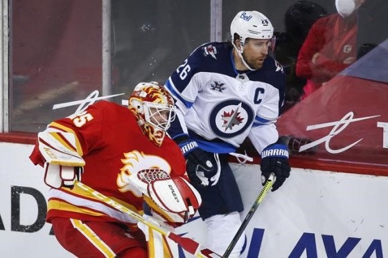 Winnipeg Jets' Blake Wheeler, right, is held up by Calgary Flames goalie Jacob Markstrom during first period NHL hockey action in Calgary on March 29, 2021. THE CANADIAN PRESS/Jeff McIntosh