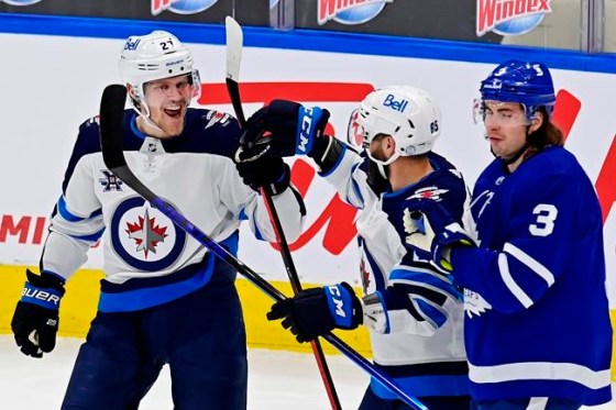 Winnipeg Jets' Nikolaj Ehlers (27) celebrates his goal against the Toronto Maple Leafs with teammate Mathieu Perreault (85) as Maple Leafs' Justin Holl (3) skates past during first-period NHL hockey action in Toronto on Thursday, April 15, 2021. THE CANADIAN PRESS/Frank Gunn