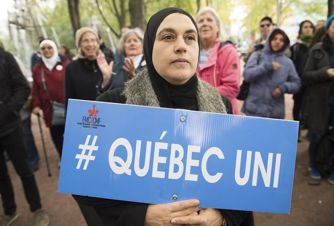 A Quebec Superior Court justice is set to issue a ruling Tuesday on the constitutionality of the province's secularism law, known as Bill 21. People hold up signs during a demonstration against Bill 21 in Montreal, Sunday, Oct. 6, 2019. THE CANADIAN PRESS/Graham Hughes