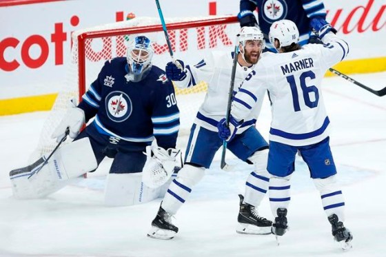 Toronto Maple Leafs' Nick Foligno (71) and Mitchell Marner (16) celebrate Marner's goal on Winnipeg Jets goaltender Laurent Brossoit (30) during second-period NHL action in Winnipeg on Thursday, April 22, 2021. THE CANADIAN PRESS/John Woods