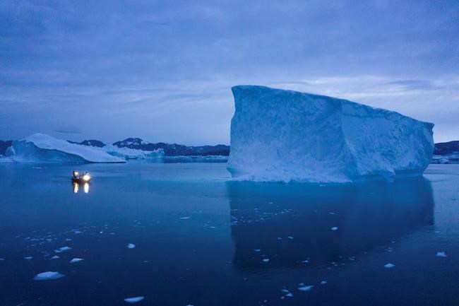 In this Aug. 15, 2019, photo, a boat navigates at night next to large icebergs in eastern Greenland. Greenland's ice has been melting for more than 20 years. THE CANADIAN PRESS/AP-Felipe Dana