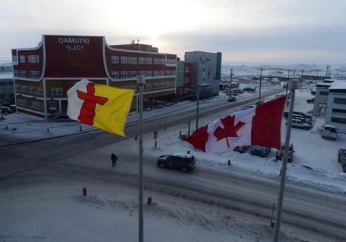 A Canada flag and the Nunavut flag fly in Iqaluit, Nunavut, on Thursday, Feb. 9, 2017. Broken isolation rules, shared cigarettes and fear of having isolation periods extended are some of the findings in a report that sheds light on how Nunavut's first cases of COVID-19 suddenly appeared in the territory last November. THE CANADIAN PRESS/Sean Kilpatrick