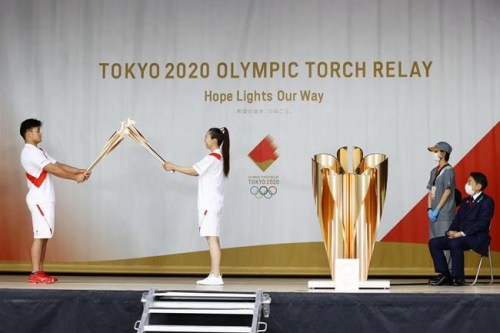 An ignition ceremony for the Tokyo Olympic torch relay is held at Heiwadai Athletic Stadium in Fukuoka, southwestern Japan, Tuesday, May 11, 2021. The torch relay was taken off public roads due to the coronavirus pandemic. The next week's torch relay is being pulled off the streets in Hiroshima prefecture, too, as COVID-19 cases rise in Japan. This is at least the sixth change to the relay - from rerouting to cancellation - in the last several weeks as cases surge in Japan. Organizers warned before the relay began that changes and delays were expected in the face of the pandemic. (Kyodo News via AP)