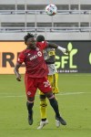 Toronto FC forward Ayo Akinola (20) heads the ball away from Columbus Crew defender Jonathan Mensah, right, during the first half of an MLS soccer match, Wednesday, May 12, 2021, in Orlando, Fla. (AP Photo/John Raoux)