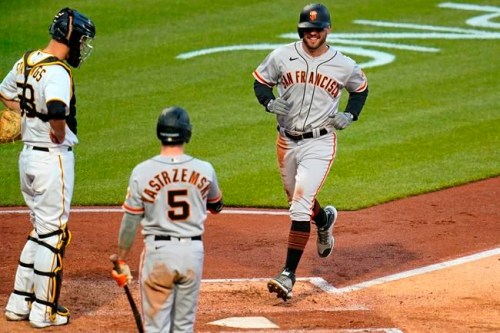 San Francisco Giants' Mike Tauchman, right, scores on an errant pickoff throw to third base by Pittsburgh Pirates catcher Jacob Stallings, left, during the fifth inning of a baseball game in Pittsburgh, Thursday, May 13, 2021.(AP Photo/Gene J. Puskar)