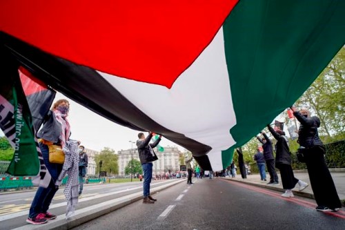 People hold a Palestinian flag as they march in solidarity with the Palestinian people amid the ongoing conflict with Israel, during a demonstration in London, Saturday, May 15, 2021. (AP Photo/Alberto Pezzali)
