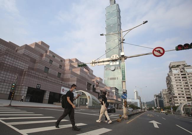 People wear face masks to protect against the spread of the coronavirus and walk past Taipei 101 building after the COVID-19 alert raise to level 3 in Taipei, Taiwan, Saturday, May 15, 2021. Taiwan, which has had enviable success in containing COVID-19, imposed new restrictions in its capital city on Saturday as it battled its worst outbreak since the pandemic began. (AP Photo/Chiang Ying-ying)
