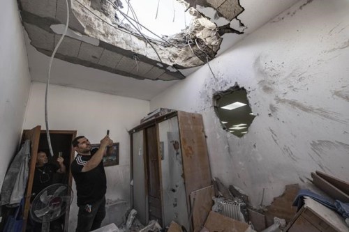 People take pictures of a damaged synagogue after it was hit by a rocket fired from the Gaza Strip, in Ashkelon, Israel, Sunday, May 16, 2021. (AP Photo/Tsafrir Abayov)