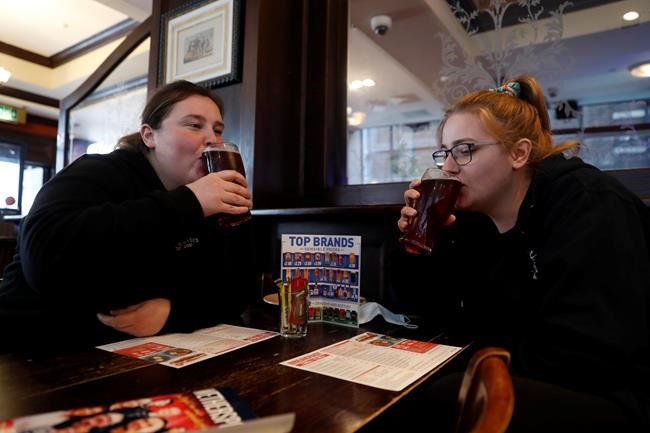 Libby Jones, right, with her colleague Shannon Maiden, both nurses from Great Ormond Street hospital who have just finished an overnight shift, have a pint of cider at the Shakespeare's Head pub, which will be reopening for the first time to serve indoor customers since the end of the latest coronavirus lockdown, in London, Monday, May 17, 2021. (AP Photo/Alastair Grant)