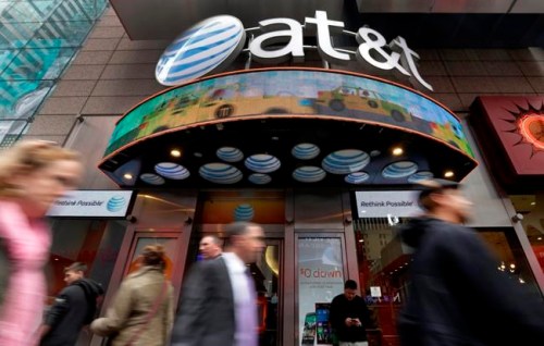 FILE - In this Oct. 21, 2014 file photo, people pass an AT&T store in New York's Times Square. AT&T will combine its media operations that include CNN HBO, TNT and TBS in a $43 billion deal with Discovery, the owner of lifestyle networks including the Food Network and HGTV. The deal announced Monday, May 17, 2021, would create a separate media company as households increasingly abandon cable and satellite TV, looking instead at Netflix, Amazon Prime Video, Facebook, TikTok and YouTube. (AP Photo/Richard Drew, File)