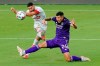 Toronto FC midfielder Jonathan Osorio, left, takes a shot on goal as Orlando City defender Kyle Smith (24) tries to block during the first half of an MLS soccer match, Saturday, May 22, 2021, in Orlando, Fla. (AP Photo/John Raoux)