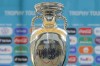 FILE - In this Sunday, April 25, 2021 file photo, journalists are reflected in the Euro 2020 soccer tournament trophy at the National Arena stadium, a tournament venue, in Bucharest, Romania. UEFA set itself a challenge deciding nine years ago to let a dozen cities around Europe host its marquee European Championship in 2020. The multi-country project means more fans can see their own team in a stadium than if Euro 2020 was being traditionally hosted by a single nation amid international travel restrictions. (AP Photo/Vadim Ghirda, File)