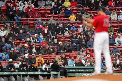 Fans watch as Boston Red Sox's Nathan Eovaldi, foreground, pitches during the first inning of a baseball game against the Miami Marlins, Saturday, May 29, 2021, in Boston. Saturday marks the end of most COVID-19 restrictions in Massachusetts. (AP Photo/Michael Dwyer)
