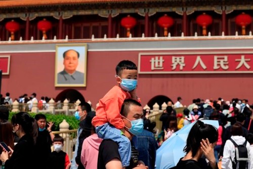 FIEL - In this May 3, 2021, file photo, a man and child wearing masks visit Tiananmen Gate near the portrait of Mao Zedong in Beijing. China’s ruling Communist Party is looking at allowing easing birth limits further to allow couples to have three children instead of two in response to the population's rising age, a state news agency said Monday, May 31, 2021. (AP Photo/Ng Han Guan, File)