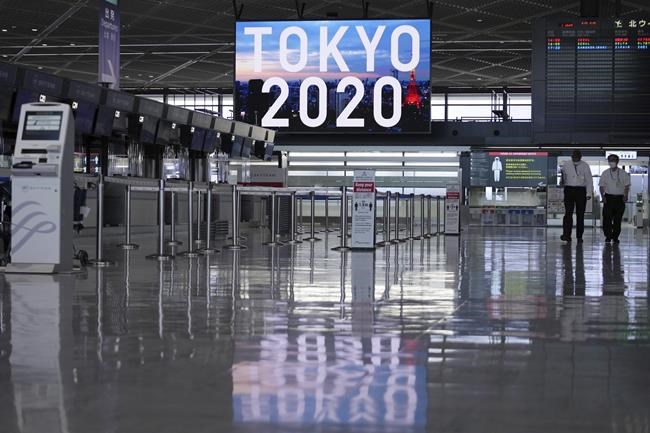 Staffs wearing protective masks to help curb the spread of the coronavirus walk in the empty ticketing area at Narita International Airport Tuesday afternoon, June 1, 2021, in Narita, east of Tokyo. A state of emergency in Tokyo, Osaka and other prefectures was last week extended until June 20 as COVID-19 cases continue to put the medical system under strain. (AP Photo/Eugene Hoshiko)