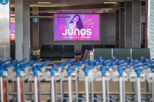 A Juno Awards sign hangs over the baggage carousels at the John G. Diefenbaker International Airport in Saskatoon on Thursday, March 12, 2020.&nbsp; Band members have had a hard time getting together, COVID-19 outbreaks have stalled filming and Ontario's third wave of the pandemic has postponed the big show twice. THE CANADIAN PRESS/Matt Smith