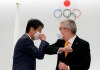 FILE - In this Nov. 16, 2020, file photo, former Japan's Prime Minister Shinzo Abe, left, and Thomas Bach, President of the International Olympic Committee (IOC), bump elbows after a ceremony to present the Olympic Order to Abe at Japan Olympic Museum in Tokyo. IOC officials say the Tokyo Olympics will open on July 23 and almost nothing now can stop the games from going forward. (Kim Kyung-hoon/Pool Photo via AP, File)