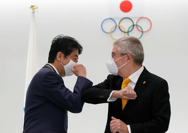 FILE - In this Nov. 16, 2020, file photo, former Japan's Prime Minister Shinzo Abe, left, and Thomas Bach, President of the International Olympic Committee (IOC), bump elbows after a ceremony to present the Olympic Order to Abe at Japan Olympic Museum in Tokyo. IOC officials say the Tokyo Olympics will open on July 23 and almost nothing now can stop the games from going forward. (Kim Kyung-hoon/Pool Photo via AP, File)