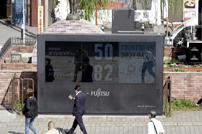 People walk by the countdown clock for the Tokyo 2020 Olympic and Paralympic Games near Shimbashi station in Tokyo, Thursday, June 3, 2021, to mark 50 days before the start of the Summer Games. (AP Photo/Kantaro Komiya)