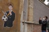 FILE - In this Thursday, April 22, 2021 file photo, a passerby stops to take a picture of a mural depicting Juventus president Andrea Agnelli puncturing a soccer ball with a knife, in Rome. Attempting to establish a European Super League was “not a coup” but rather “a desperate cry of alarm for a system that, knowingly or not, is heading towards insolvency,” Juventus president Andrea Agnelli said Friday. Along with Real Madrid and Barcelona, Juventus is one of the few remaining holdouts refusing to renounce the failed Super League among the 12 founders of the project. (AP Photo/Andrew Medichini, File)