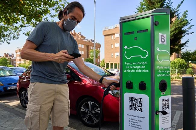 A man charges his electric car at an electrical charging point in Rivas Vaciamadrid, Spain, Tuesday, June 15, 2021. Spain is Europe's second-leading car maker but it is lagging behind when it comes to electric cars, a situation that the government aims to change by using around five billion euros of the EU pandemic recovery funds to kickstart the electric car industry. The government plans to spend big, to install a network of public recharging stations and to convince customers about the benefits of buying electric or hybrid vehicles. (AP Photo/Manu Fernandez)