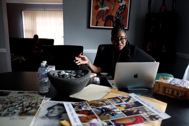 Kimberly Ross-Holmes works on her laptop at her home in Evanston, Friday, April 23, 2021. The Chicago suburb will become the first to pay reparations in the form of housing grants. She said she is glad that Juneteenth will be a federal holiday, but hopes that the federal government takes up more issues that affect the everyday lives of Black people. (AP Photo/Shafkat Anowar)