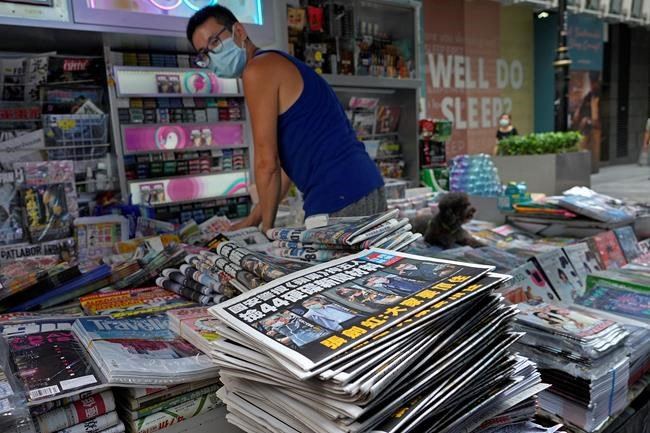 A vendor adjusts copies of Apple Daily at a news stand at a downtown street in Hong Kong Friday, June 18, 2021. The pro-democracy paper increased its print run to 500,000 copies on Friday, a day after police arrested five top editors and executives and froze $2.3 million in assets linked to the media company. (AP Photo/Vincent Yu)