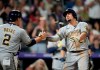 Milwaukee Brewers' Luis Urias, left, congratulates Willy Adames, who crosses home plate after hitting a two-run home run off Colorado Rockies relief pitcher Tyler Kinley during the ninth inning of a baseball game Saturday, June 19, 2021, in Denver. (AP Photo/David Zalubowski)