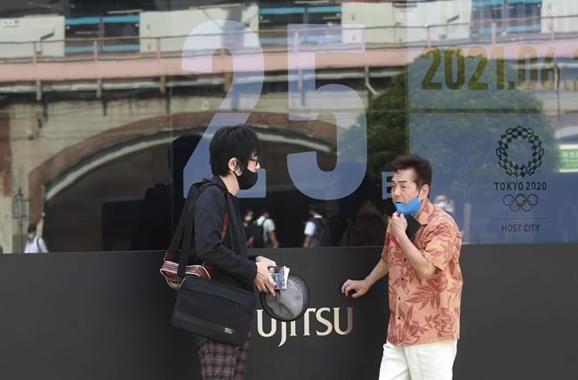 People talk by as a countdown clock shows 25 days to the opening ceremony of the Tokyo 2020 Olympic and Paralympic Games, in Tokyo, Monday, June 28, 2021. (AP Photo/Koji Sasahara)
