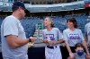 Gwen Goldman, 70, center, speaks with New York Yankees manager Aaron Boone on the field before assuming her duties as a bat girl during a baseball game between the Yankees and the Los Angeles Angels, Monday, June 28, 2021, at Yankee Stadium in New York. Goldman wrote to Yankees general manager as a 10-year-old asking to be a bat girl, but was told she had no place in the dugout. Thanks to current Yankees manager Brian Cashman, Goldman got her wish on the first day of HOPE week Monday. Goldman's daughter Abby, right, looks on. (AP Photo/Kathy Willens)