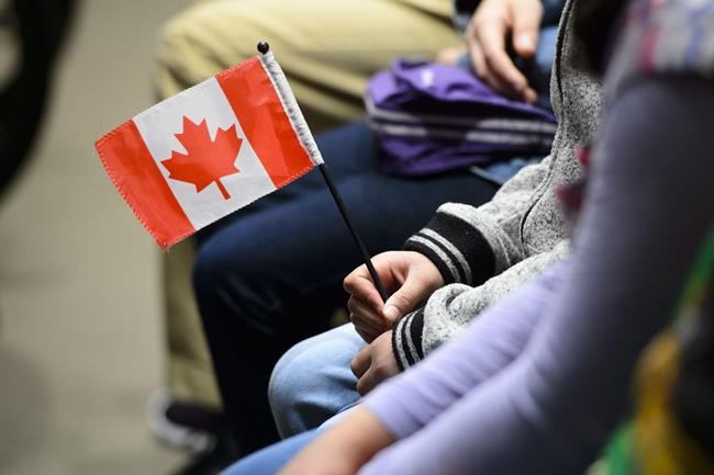 A young new Canadian holds a flag as she takes part in a citizenship ceremony on Parliament Hill in Ottawa on April 17, 2019. It will be a muted Canada Day in many parts of the country as grief and anger over the discovery of hundreds of unmarked graves at former residential schools has made it hard for many Canadians to stomach the usual patriotic pomp of July 1. Rather than fireworks, parades and performances, several municipalities say they will mark the national holiday with reflection and solidarity, but Indigenous leaders, advocates and scholars say that's just the start of broad efforts needed to reframe Canada Day as a reminder of the country's dark past and present, and what it means to be Canadian. THE CANADIAN PRESS/Sean Kilpatrick