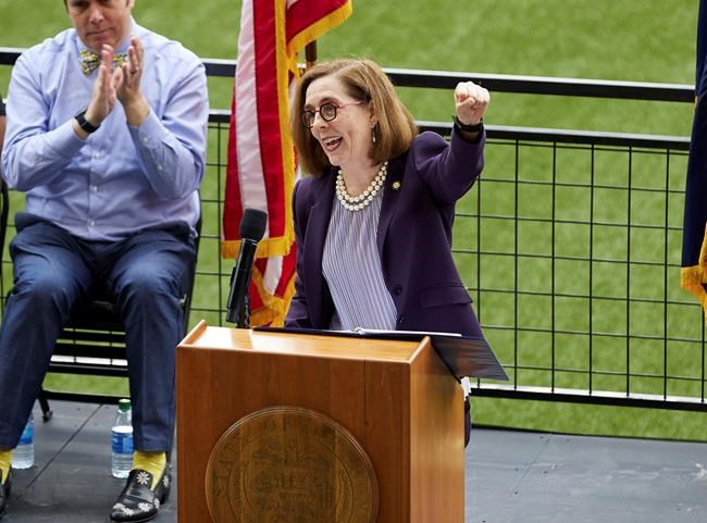 Oregon Governor Kate Brown pumps her fist while announcing the end of the state's COVID-19 restrictions in Portland, Ore., Wednesday, June 30, 2021. (AP Photo/Craig Mitchelldyer)
