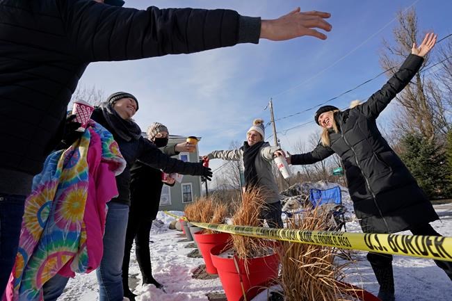 FILE — Canadians Stephanie Frizzell, far right, and her daughter, Shelby Dubois, second from right, move in for a big air hug with their American relatives, Christian Gervais, far left, Sherie Frizzell, second from left, and Caitlin Davis, third from left, after a visit at the U.S.-Canadian border of Stanstead, Quebec and Derby Line, Vt., in this Dec. 19, 2020, file photo. Since shortly after the border closed in March 2020, people from both countries traveled to Derby Line, and Stanstead, to hold impromptu family reunions from their own side of the border on a residential street. It's high summer along the border between the United States and Canada and people on both sides are wondering when the two governments will ease border-crossing restrictions imposed at the beginning of the COVID-19 pandemic. (AP Photo/Elise Amendola, File)
