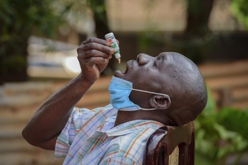 A man with a cough but who had not been tested for the coronavirus uses COVIDEX, a locally-made herbal medicine approved by the government for use as a supportive treatment for viral infections, in Kampala, Uganda Tuesday, July 6, 2021. Some hospitals with COVID-19 wards are charging prohibitive sums for most Ugandans and many are now self-medicating within their homes, experimenting with everything from traditional medicine to a newly approved herbal remedy selling briskly as COVIDEX. (AP Photo/Nicholas Bamulanzeki)