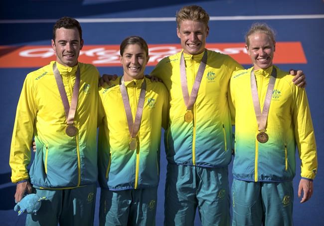 FILE - In this April 7, 2018 file photo, Australia's gold medal mixed relay triathlon team, from left, Jacob Birtwhistle, Ashleigh Gentle, Matthew Hauser, and Gillian Backhouse, stand with their medals at the Southport Broadwater Parklands during the 2018 Commonwealth Games on the Gold Coast, Australia. Gentle, is looking forward to possibly representing her country again when the mixed team format makes its Olympic debut in Tokyo. That'll be in addition to her place in the women's individual race. (AP Photo/Mark Schiefelbein, File)