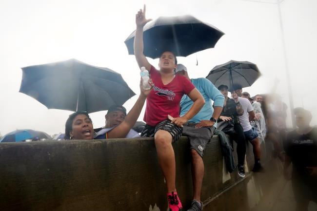 Demonstrators sit on the median separating the north and south bound lanes of the Palmetto Expressway, Tuesday, July 13, 2021, in Miami. The demonstrators voiced support for Cubans, who had taken to the streets of several communities around the communist nation on Sunday to air grievances over poor economic conditions, among other complaints. (AP Photo/Marta Lavandier)